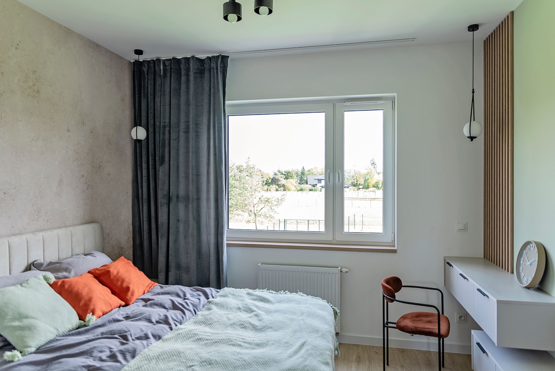 Modern and comfortable bedroom with double bed with orange pillow and blanket. Home interior with window and real estate.